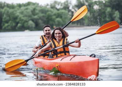 Happy young couple in sea vests is smiling while sailing a kayak - Powered by Shutterstock