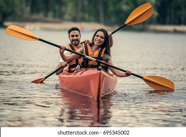 Happy Young Couple In Sea Vests Is Smiling While Sailing A Kayak