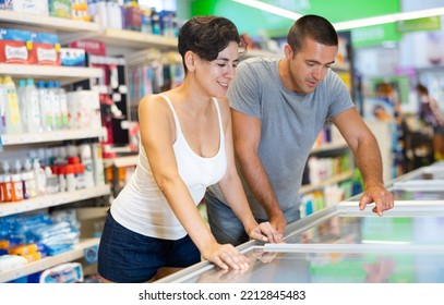 Happy Young Couple Shopping In Supermarket, Choosing Frozen Convenience Food For Quick Dinner..