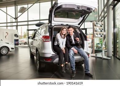 Happy Young Couple Sitting At Back Of Car