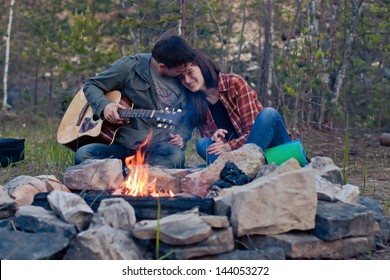 	Happy Young Couple Sitting By Bonfire