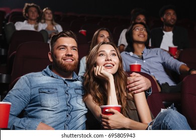Happy young couple sitting at the cinema and enjoys watching the movie