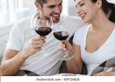 Happy Young Couple Sitting And Drinking Wine At Home