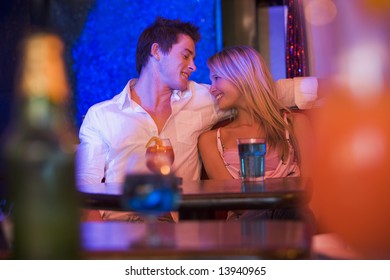Happy young couple sitting in a nightclub, smiling at each other - Shutterstock ID 13940965