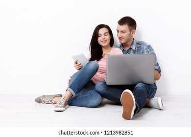 Happy young couple sitting on the floor with a laptop looking for their new home and furniture. Mock up for design. - Shutterstock ID 1213982851