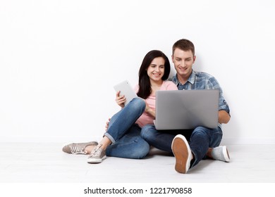 Happy young couple sitting on the floor with a laptop looking for their new home and furniture. Mock up for design. - Shutterstock ID 1221790858