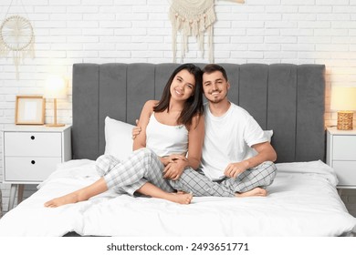 Happy young couple sitting on bed at home - Powered by Shutterstock