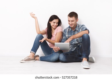 Happy young couple sitting on the floor using a tablet for shopping and entertainment. Mock up. - Shutterstock ID 527357218