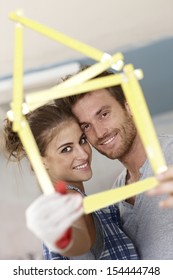 Happy Young Couple Smiling Through Little House Formed By Ruler, DIY.