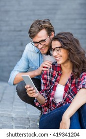 Happy Young Couple In Spectacles Using Mobile Phone