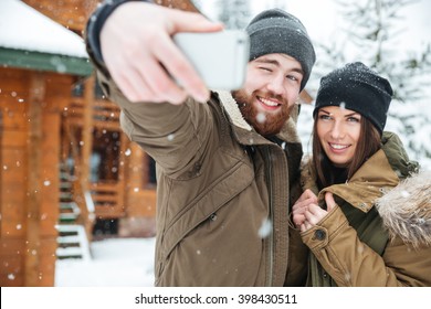 겨울에는 눈 내리는 날씨에 서서 셀카를 만드는 행복한 젊은 커플들 스톡 사진