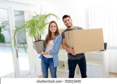 Happy Young Couple Student Roommate Packing Boxes And Moving Furniture During Their Move Into New Home Flat Apartment