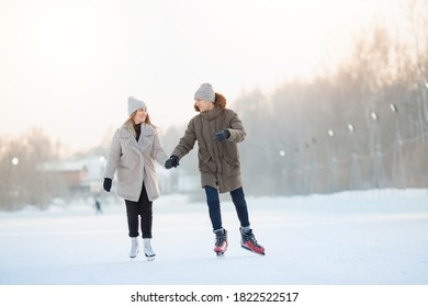 Happy Young Couple In Sunny Winter Nature Ice Skating.