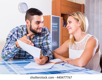 Happy Young Couple At The Table Filling Forms For Joint Banking Account
