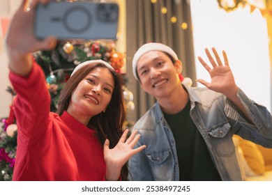 Happy young couple taking selfie in festive attire, celebrating holiday season with joy and cheer. vibrant decorations create warm atmosphere. - Powered by Shutterstock