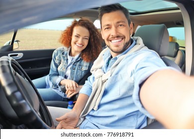 Happy Young Couple Taking Selfie In Car