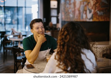 Happy young couple talking over a cup of coffee in a cafe, man and woman in a coffee shop on a date. - Powered by Shutterstock