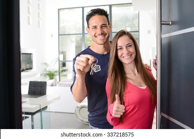 Happy Young Couple At Their New House Front Door Proud To Show Home Keys