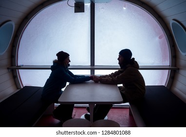 Happy Young Couple Travelers On Vacation Looking At Each Other And Holding Hands Inside Of Hotel Ski Resort In The Mountains