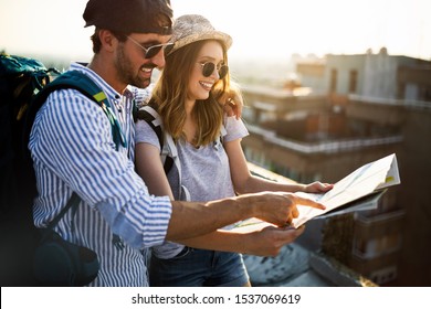 Happy young couple of travellers holding map and having fun