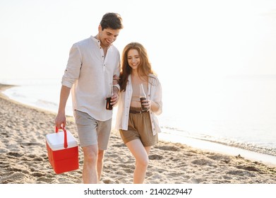 Happy Young Couple Two Friend Family Man Woman In White Clothes Hold Beer Bottle Bag Refrigerator Have Picnic Rest Together At Sunrise Over Sea Beach Ocean Outdoor Seaside In Summer Day Sunset Evening