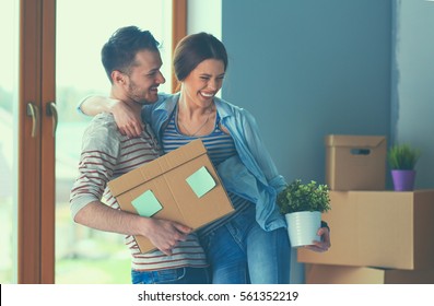 Happy Young Couple Unpacking Or Packing Boxes And Moving Into A New Home