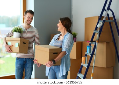 Happy Young Couple Unpacking Or Packing Boxes And Moving Into A New Home