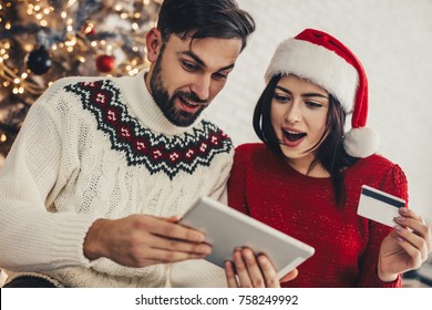 Happy Young Couple Using Credit Card To Shop Online. Happy Young Man And Woman With Laptop And Credit Card Buying Online. Online Christmas Shopping.