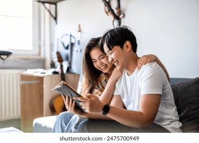 Happy young couple using digital tablet together on the sofa at home

 - Powered by Shutterstock