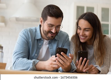 Happy Young Couple Using Smartphones Together, Smiling Beautiful Wife And Husband Having Fun With Phones, Watching Funny Video In Social Network, Playing Mobile Games, Reading Good News