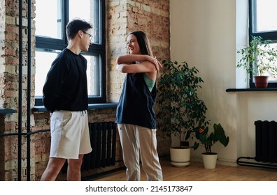 Happy Young Couple Of Vogue Dancers In Activewear Communicating With Each Other In Modern Studio Of Choreography Before Repetition