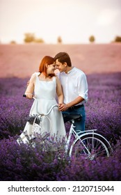 Happy Young Couple Is Walking In The Lavender Field With White Bicycle.