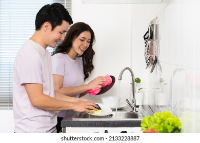 happy young couple washing dishes together in the sink in the kitchen at home - Shutterstock ID 2133228887
