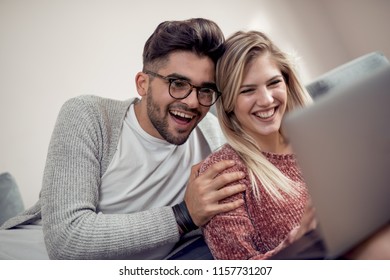 Happy Young Couple Watching A Favourite Movie While Sitting In A Living Room.