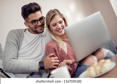 Happy Young Couple Watching A Favourite Movie While Sitting In Living Room.