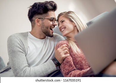 Happy Young Couple Watching A Favourite Movie While Sitting In Living Room.