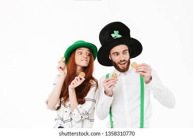 Happy young couple wearing costumes, celebrating St.Patrick 's Day isolated over white background, holding golden bitcoins - Powered by Shutterstock