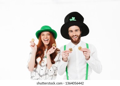 Happy young couple wearing costumes, celebrating St.Patrick 's Day isolated over white background, holding golden bitcoins - Powered by Shutterstock