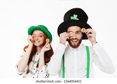 Happy young couple wearing costumes, celebrating St.Patrick 's Day isolated over white background, holding golden bitcoins - Powered by Shutterstock