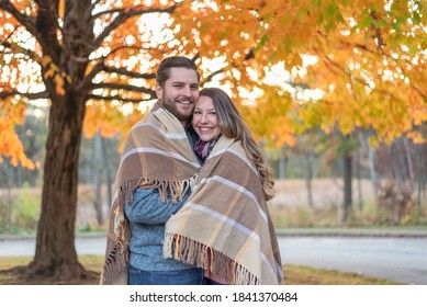 Happy young couple wrapped in a blanket in fall - Powered by Shutterstock