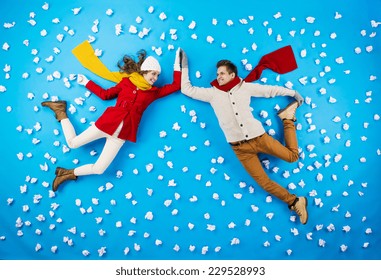 Happy young couplein winter clothes having fun against the blue background with snowflakes - Powered by Shutterstock