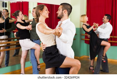 Happy Young Couples Having Tango Class At Dance Studio. Selective Focus
