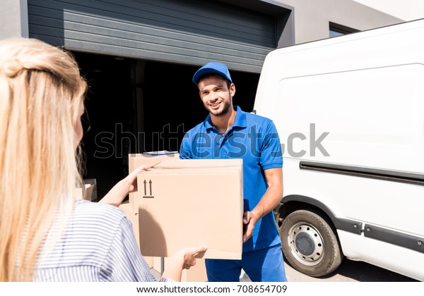 happy young courier\
giving package to woman