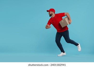 Happy young courier running to deliver parcel on light blue background, space for text - Powered by Shutterstock