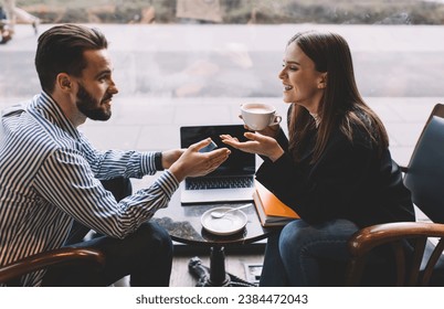 Happy young coworkers having coffee break in cozy cafe and chatting - Powered by Shutterstock