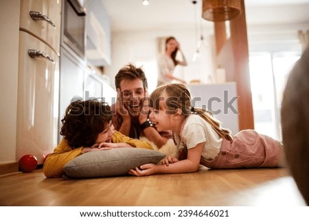 Happy young dad having fun with his kids on the floor at home