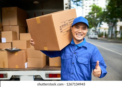 Happy Young Delivery Man With Big Cardboard Box Showing Thumbs-up And Smiling At Camera