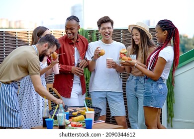 Happy Young Diverse Friends Eating Burgers And Drinking Lemonade At Barbecue Patio Party. Cheerful Excited People Having Fun At Bbq Lunch. Youth Lifestyle, Summer And Friendship Concept. Portrait