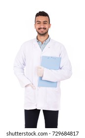 Happy young doctor in white lab coat smiling and holding a clipboard, isolated on white background