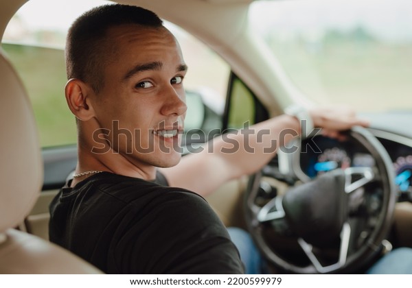 Happy young\
driver sitting in his car with\
smile